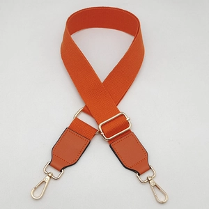 Detail of adjustable orange canvas shoulder strap with light gold metal swivel hooks