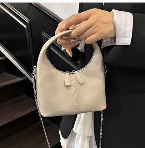 Détail du sac hobo beige montrant les coutures verticales et les doubles chaînes