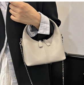 Détail du sac demi-lune blanc crème minimaliste avec chaîne argentée et fermeture éclair