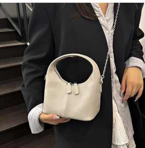 Détail du sac à main en cuir beige souple avec chaîne argentée et double fermeture éclair