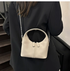 Détail du sac demi-lune en cuir beige souple avec chaîne argentée et double fermeture