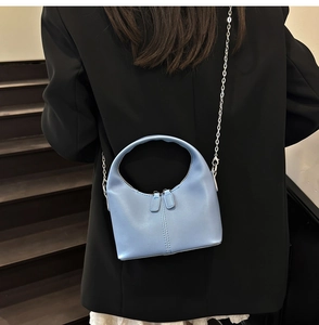 Détail du sac à main demi-lune bleu clair avec chaîne argentée et doubles fermetures