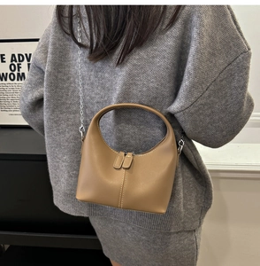 Détail du sac demi-lune en cuir kaki avec double fermeture éclair et chaîne argentée