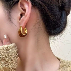 U-shaped gold hoop earrings with brown marble resin accents worn by a model