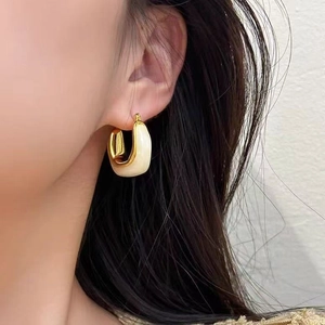 U-shaped gold amber earrings on female model with ivory enamel accents for elegant look