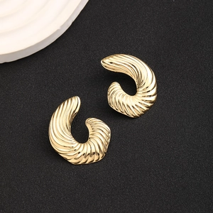 Detailed top view of gold-finished twisted metal earrings with spiral texture on black base