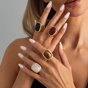 Detailed view of chunky gold rings with inset bohemian style gemstones and etched rope edges