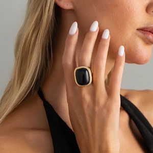 Close-up of a vintage gold ring featuring a large square black gemstone with rope edge