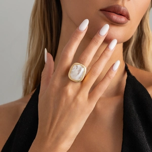Close-up of a chunky vintage gold statement ring with a white marble stone on a model hand