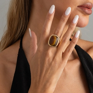 Macro detail of retro gold ring featuring a square tiger eye stone with twisted border