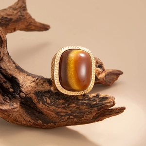 Macro shot of vintage gold ring with rectangular tiger eye stone on dark wood base