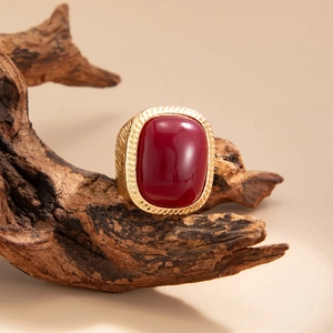 Detailed close-up of a vintage gold ring featuring a large oval red gemstone on wood