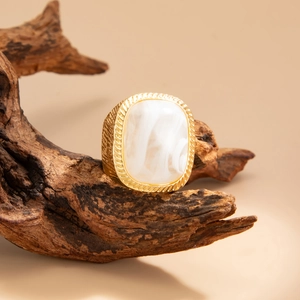 Detail of vintage gold ring with rectangle white marble stone on a piece of wood