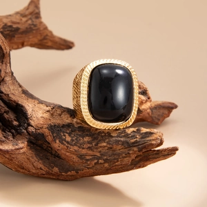 Detail of vintage gold ring with large oval black stone set on rustic wood background