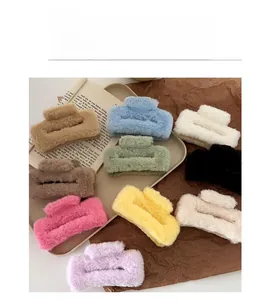 Detailed top view of various colored plush hair claw clips on a warm wooden background