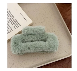 Detailed view of mint green plush hair claw clip on an aesthetic tray with books