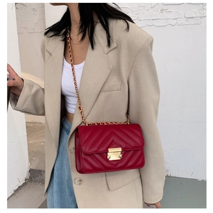Chic red quilted leather crossbody bag with gold chain strap worn with a beige blazer