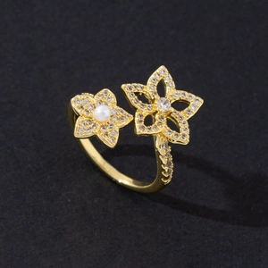 Macro detail of gold plated open ring featuring double floral design with pearls and zircons
