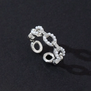 Macro shot of chain-link ring with micro-pave zircons and pearls on silver band