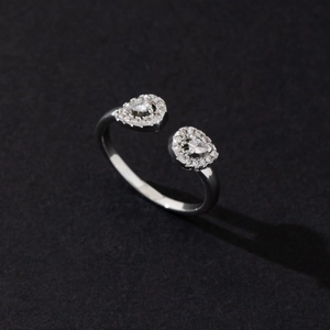 Close-up of adjustable silver ring featuring two heart shapes pave-set with white zircons