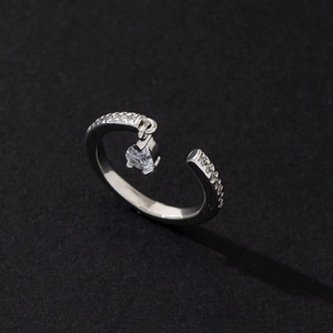 Macro detail of silver adjustable ring with pavé zircons and a heart crystal pendant