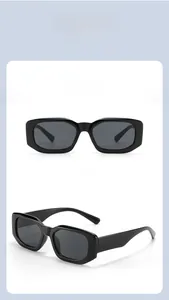 Detail view of glossy black rectangle sunglasses with dark gray lenses and thick retro frame