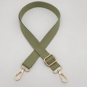 Détail d'une bandoulière en toile vert militaire avec des mousquetons dorés brillants
