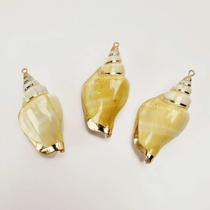 Detailed view of three cream natural shell pendants with golden electroplated metal edges