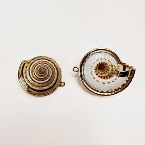 Macro detail of natural shell spiral pendants with gold plated edges for DIY jewelry making