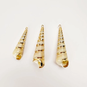 Close-up of three natural spiral shell pendants with gold plated edges for DIY jewelry