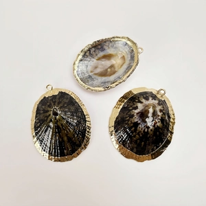 Detailed view of three natural seashell pendants with gold plated edges for DIY jewelry