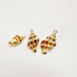 Detailed macro view of three gold-plated natural conch shell pendants for DIY jewelry making