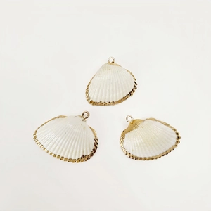 Macro shot of three natural white shell pendants with elegant gold plated metal edges