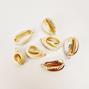 Close-up of seven natural cowrie shell pendants with gold electroplated edges for DIY jewelry