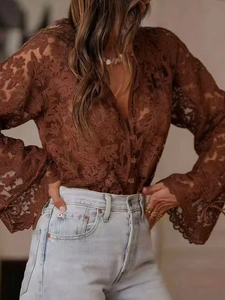 Dettaglio di camicia in pizzo floreale traforato marrone con bottoni frontali