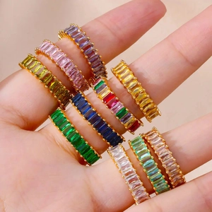 Close-up of golden rings set with colorful baguette-cut stones on a model's hand