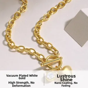 Macro detail of gold OT toggle necklace with heart pendant and cubic zirconia stone