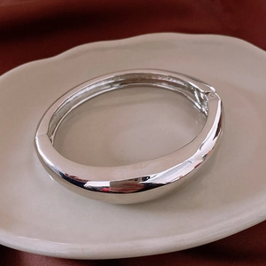 Close-up of polished silver asymmetrical wide cuff bracelet on elegant red velvet background