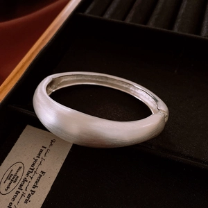 Detail of matte silver wide-open bangle with brushed finish and hinge closure