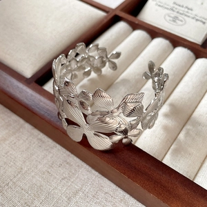 Detail of silver asymmetrical wide open cuff bracelet with 3D floral petal textures