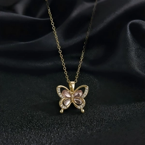 Gros plan du collier papillon doré avec pierres roses sur fond de soie noire