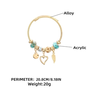 Dettaglio di un bracciale dorato a sfere con perline in acrilico verde e ciondoli a cuore