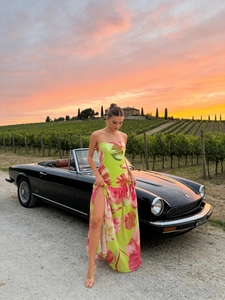 Robe longue fleurie bustier avec fente latérale devant une voiture de collection