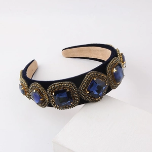 Close-up of a blue velvet headband featuring ornate sapphire crystals and gold rhinestones