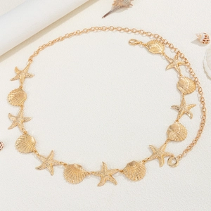 Macro shot of gold sea shell and starfish charms on a metallic hip chain accessory