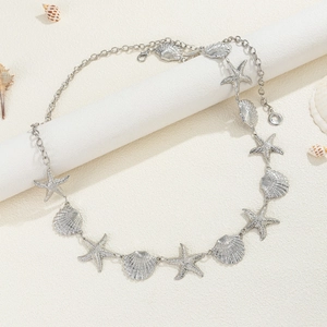 Close-up of silver starfish and seashell charms on a textured metal hip body chain