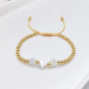 Detail of adjustable beaded bracelet with gold beads and white star shell charms