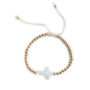 Detail of adjustable gold beaded bracelet featuring a white shell cross pendant charm