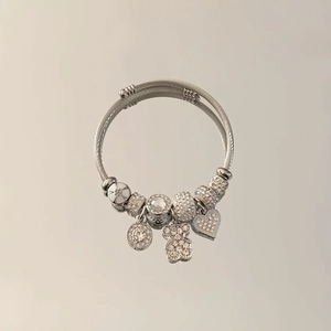 Detail of adjustable silver bangle featuring bear and heart charms with crystal beads