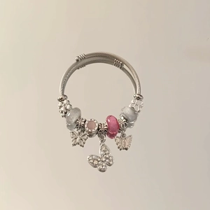 Macro view of stainless steel charm bracelet featuring pink beads and butterfly pendants